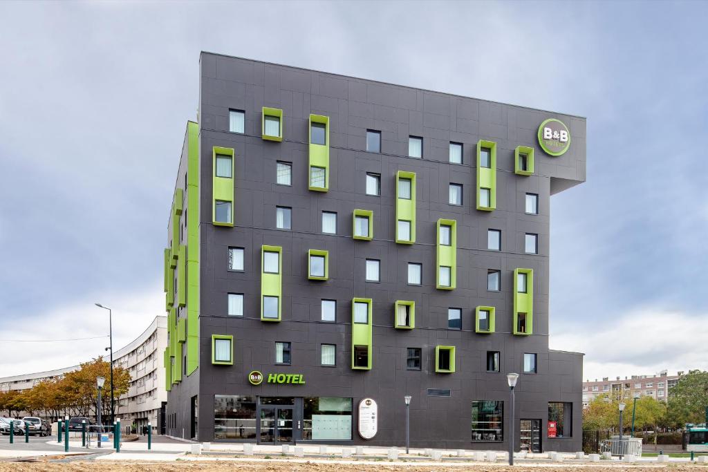 a large building with green and gray at B&B HOTEL Paris Gennevilliers Asnières in Gennevilliers