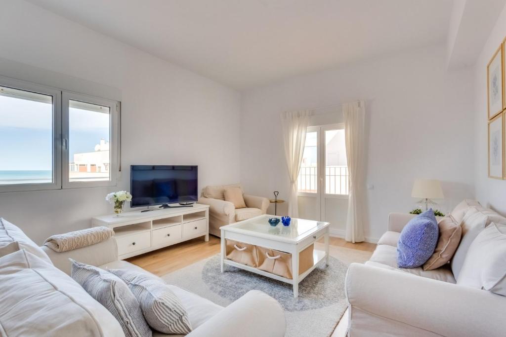 sala de estar con muebles blancos y TV de pantalla plana en FARO Family Home by Cadiz4Rentals en Cádiz