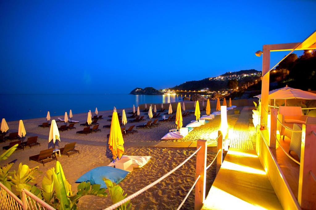 a beach with a bunch of umbrellas and chairs at Hotel Caparena in Taormina