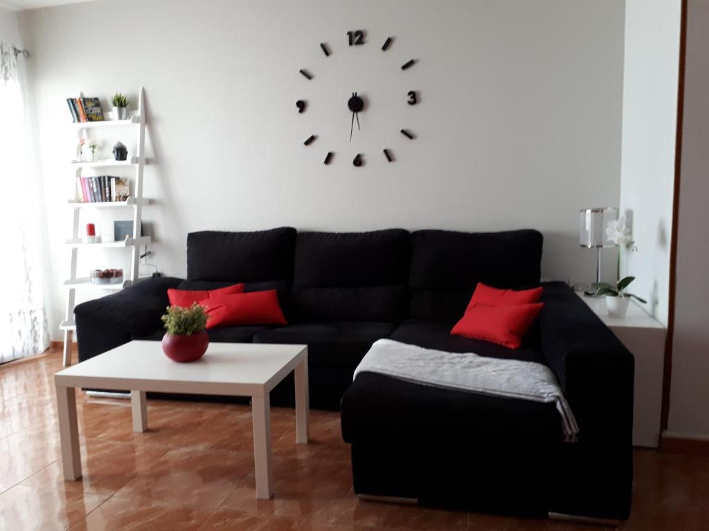 a living room with a black couch and a clock on the wall at apartamento MAKTUB in Puerto del Carmen