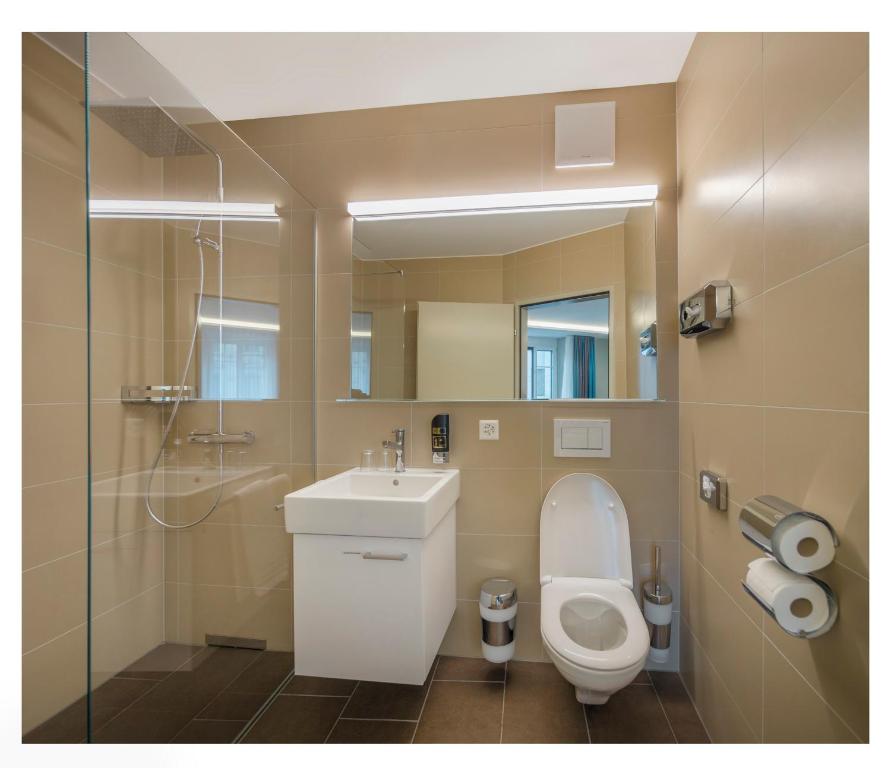 Un baño con inodoro, lavabo y espejo. en Trip Inn Zurich Hotel, en Zúrich