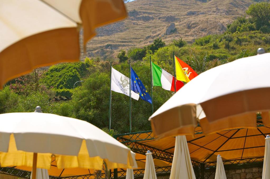 a group of flags in front of a building with umbrellas at Hotel Caparena in Taormina