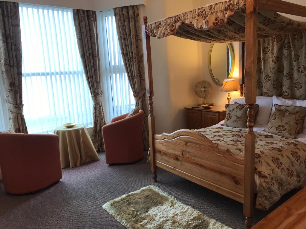 een slaapkamer met een hemelbed en 2 stoelen bij Belmont Hotel in Blackpool