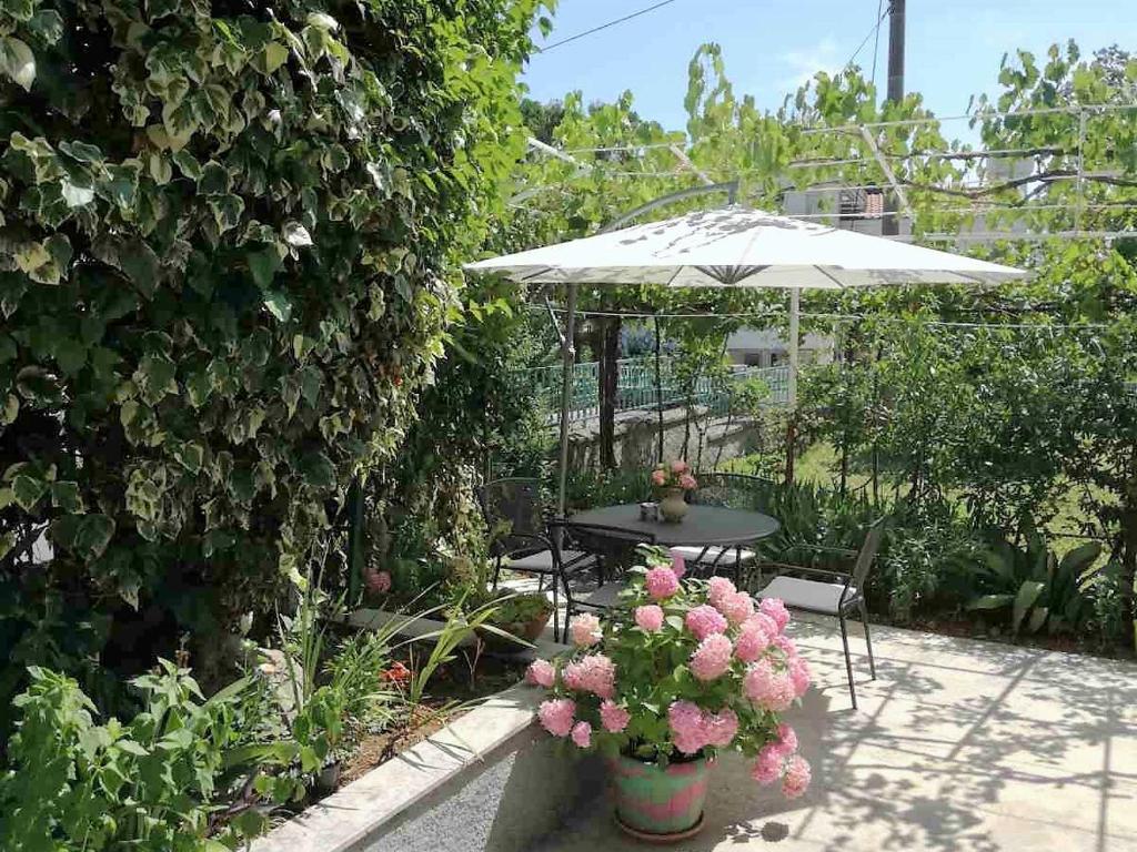 eine Terrasse mit einem Tisch, einem Sonnenschirm und Blumen in der Unterkunft Tanja in Opatija