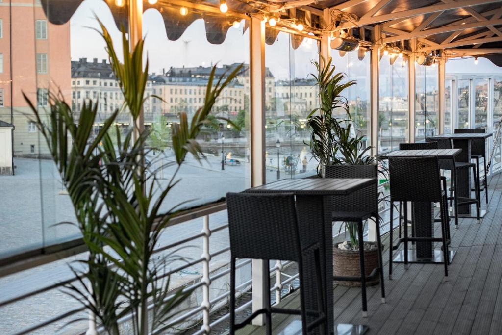 a row of tables and chairs on a balcony with plants at Mälardrottningen Yacht Hotel in Stockholm