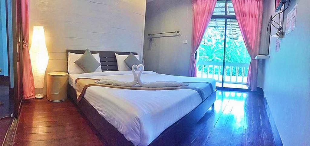 a bedroom with a white bed with a window at Marina hut guest house in Ko Lanta