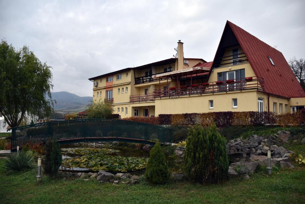 a large house with a bridge over a pond at Penzión Koruna in Nitrianske Rudno
