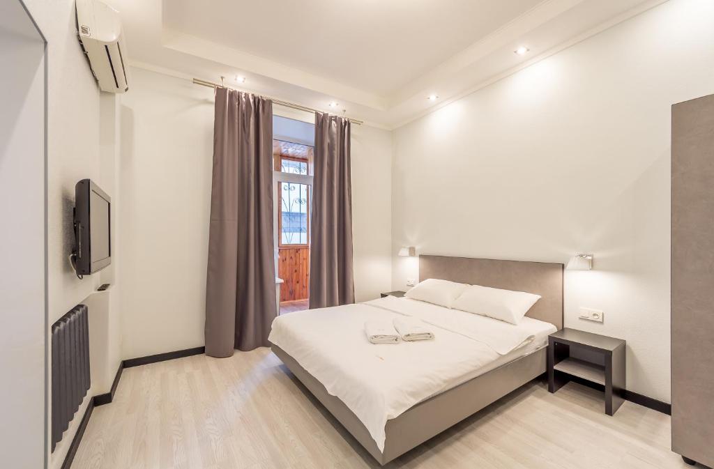 ein weißes Schlafzimmer mit einem Bett und einem TV in der Unterkunft Apartments on Lysenka 3 near Golden Gate in Kiew