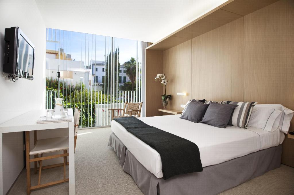 a bedroom with a bed and a desk and a window at Alenti Sitges Hotel in Sitges