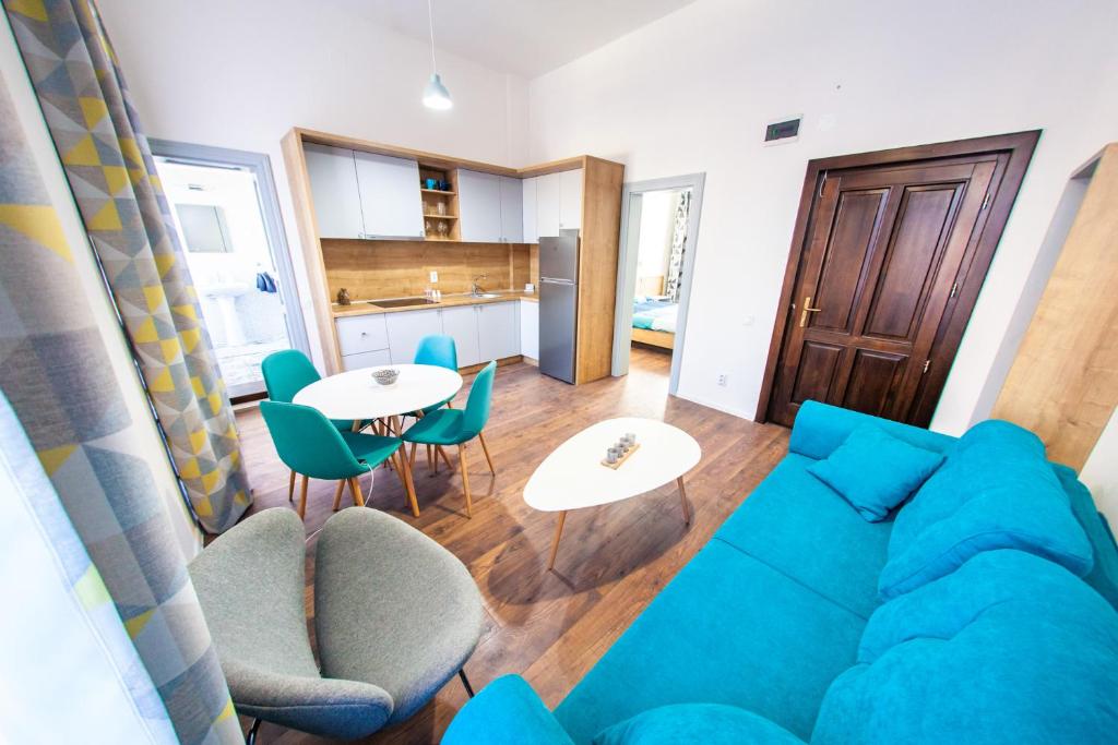 ein Wohnzimmer mit einem blauen Sofa, einem Tisch und Stühlen in der Unterkunft Central Luxury 1 in Cluj-Napoca