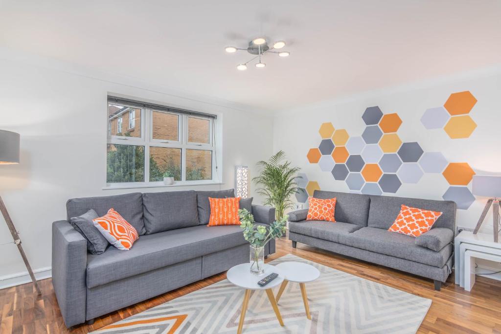 sala de estar con 2 sofás grises y almohadas de color naranja en Wing House en Hemel Hempstead