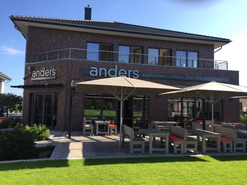 a restaurant with tables and umbrellas in front of a building at anders Kontorhaus Hotel in Lüneburg