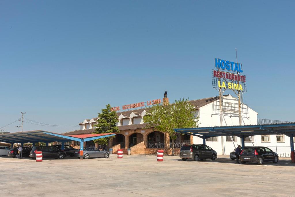 a parking lot with cars parked in front of a building at Hotel-Restaurante La Sima in Castillo de Garcimuñoz