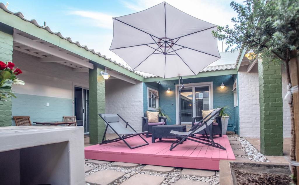 a patio with two chairs and an umbrella at Puza Moya Guest House in Langebaan