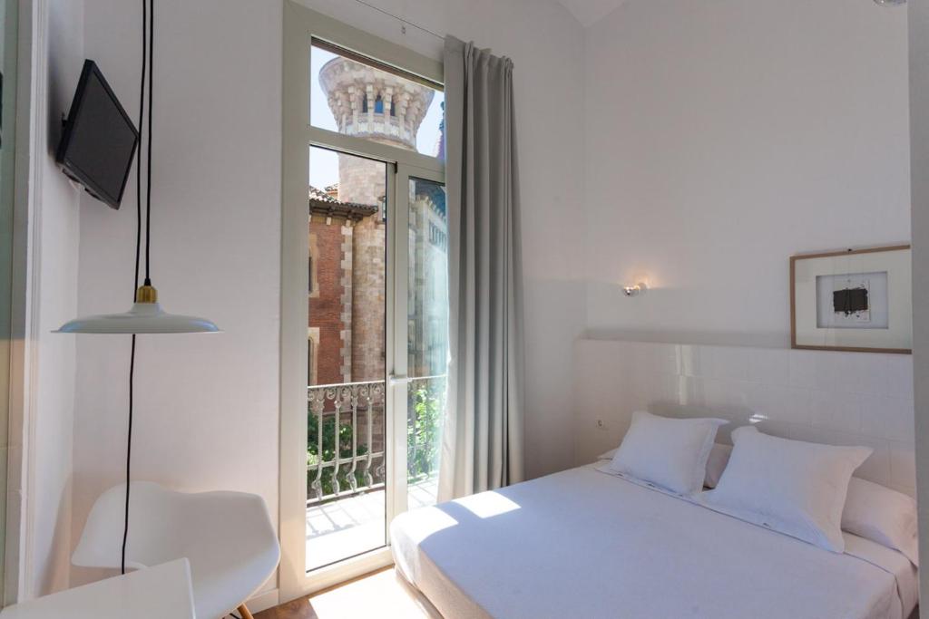 a bedroom with a white bed and a window at Hostal Argo in Barcelona