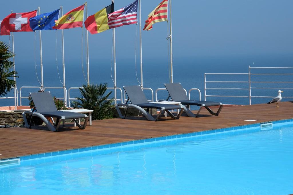 - une piscine avec des chaises et des drapeaux sur une terrasse dans l'établissement Le Catalan, à Banyuls-sur-Mer