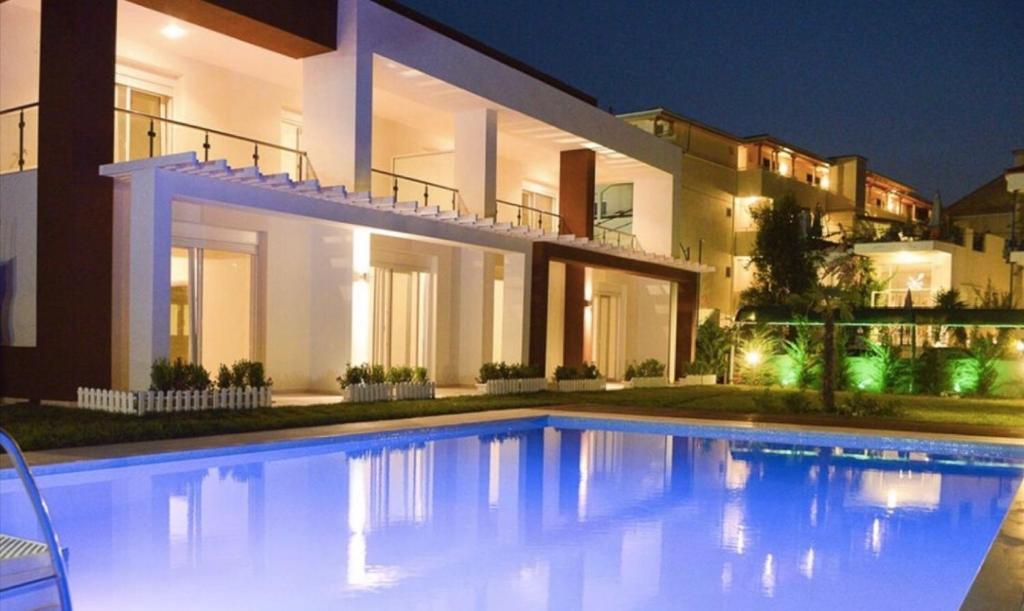 a swimming pool in front of a house at night at EllinFos ApartHotel in Hanioti