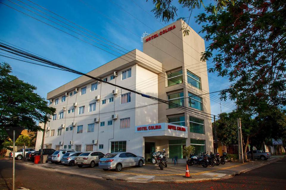 a white building with cars parked in front of it at Hotel Colina in Foz do Iguaçu