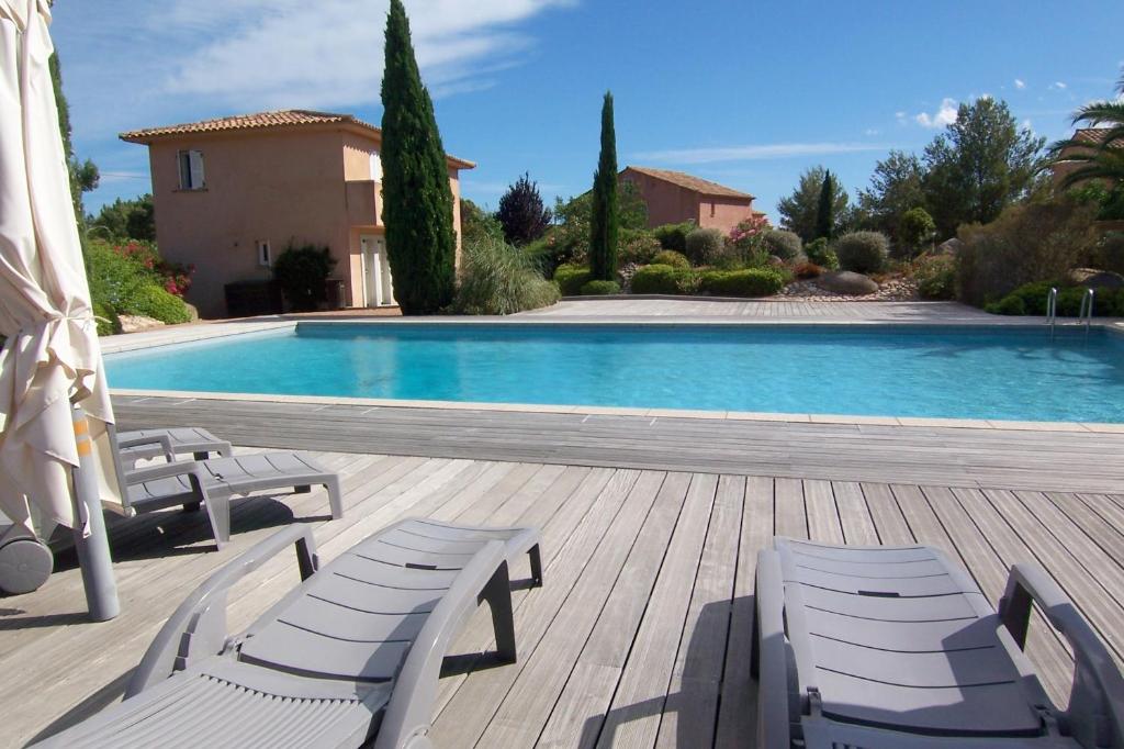 a swimming pool with two chairs and a house at CYRNOS in Porto-Vecchio