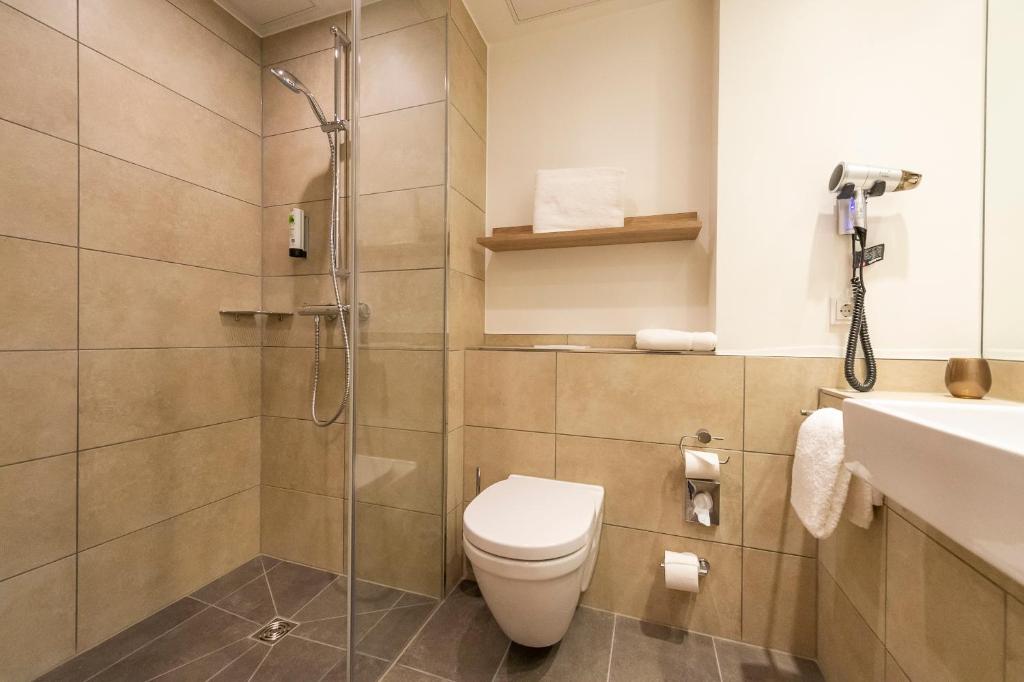 a bathroom with a shower and a toilet and a sink at HARBR. hotel Konstanz in Konstanz
