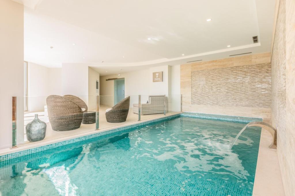 a swimming pool in a house with chairs and a swimming pool at Caneiros Luxury House & Suites in Ferragudo