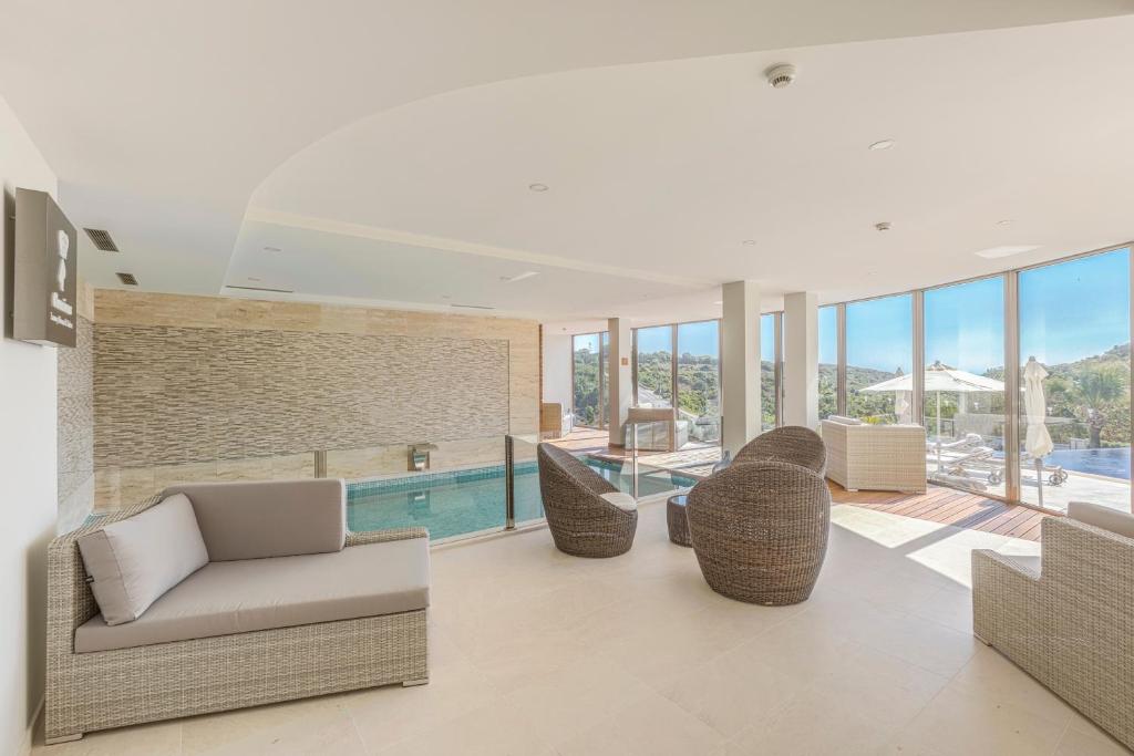 a living room with a swimming pool and chairs at Caneiros Luxury House & Suites in Ferragudo