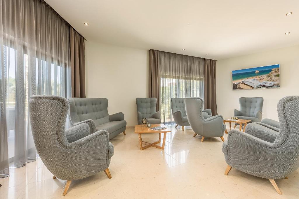 a waiting room with chairs and tables and windows at Caneiros Luxury House & Suites in Ferragudo