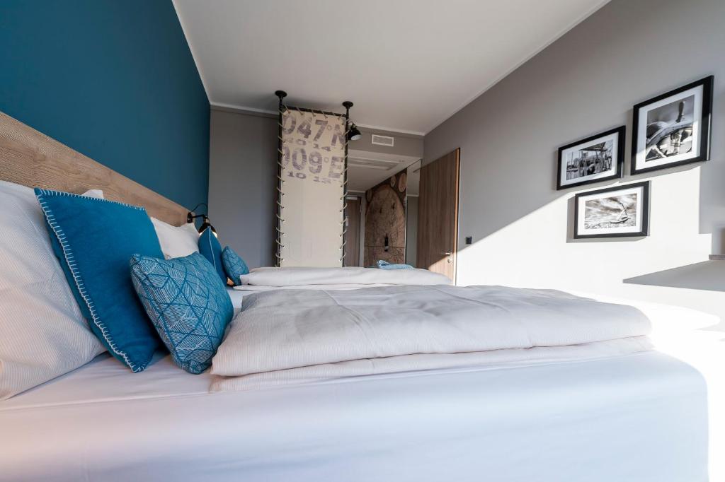 a bedroom with two beds with blue walls at HARBR. hotel Konstanz in Konstanz