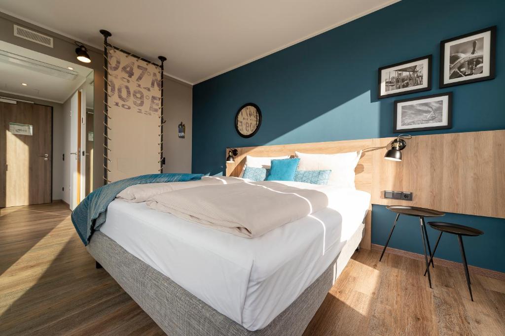a bedroom with a large bed with a blue wall at HARBR. hotel Konstanz in Konstanz