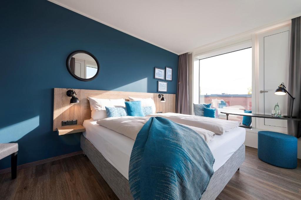 a bedroom with a large bed with a blue wall at HARBR. hotel Konstanz in Konstanz