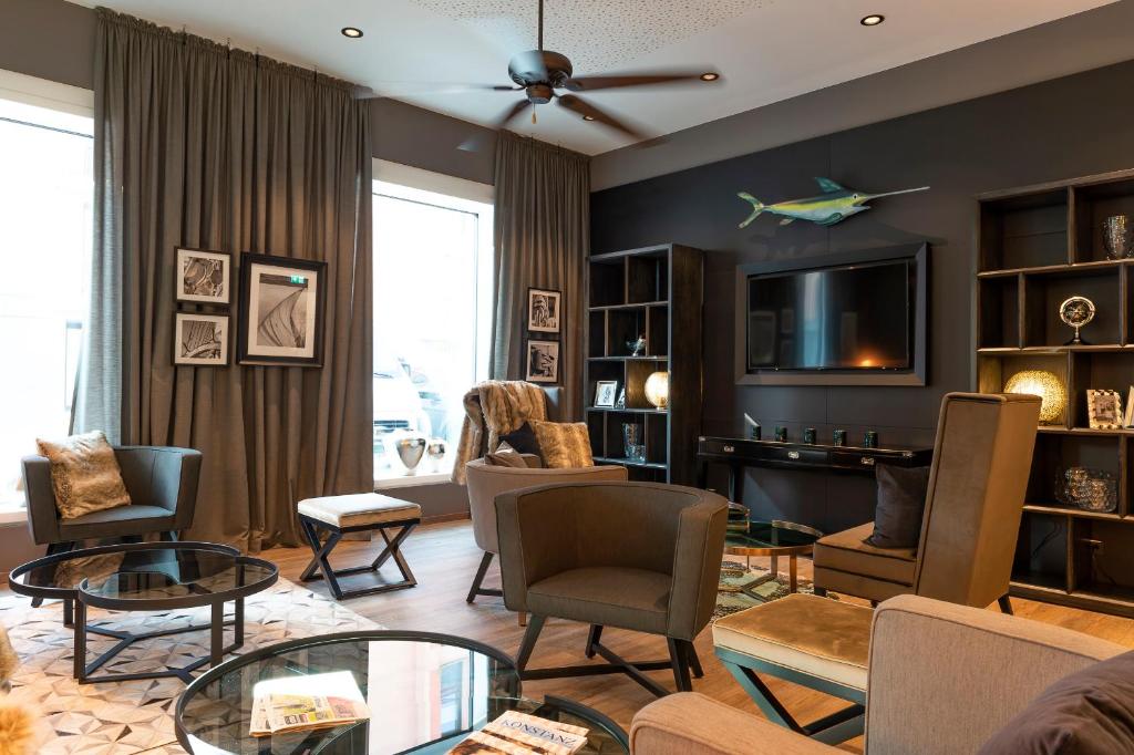 a living room with chairs and tables and a tv at HARBR. hotel Konstanz in Konstanz