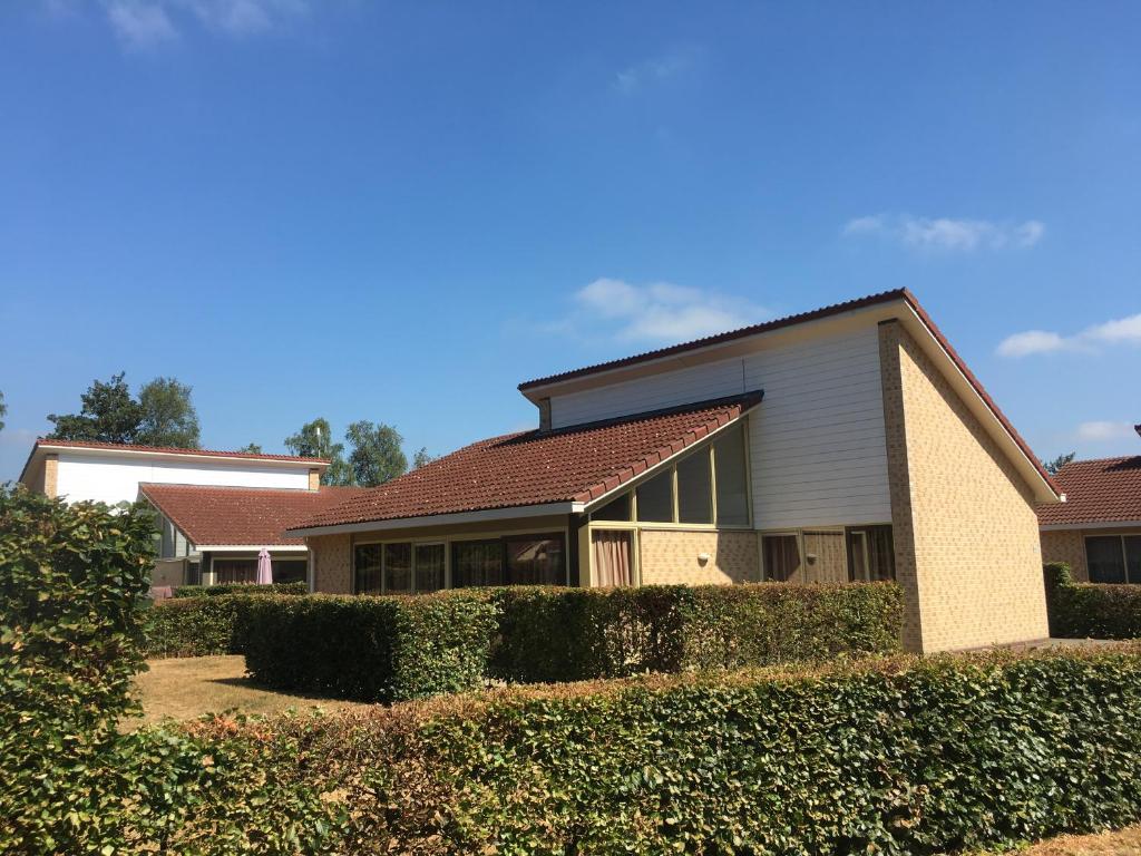 a house with a hedge in front of it at Lindenbergh Ommen in Ommen