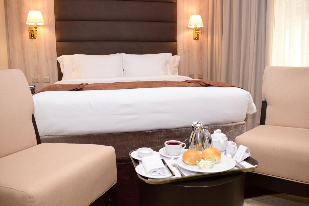 Zimmer mit einem Bett und einem Tablett mit Speisen in der Unterkunft Monty Suites & Golf in Uyo