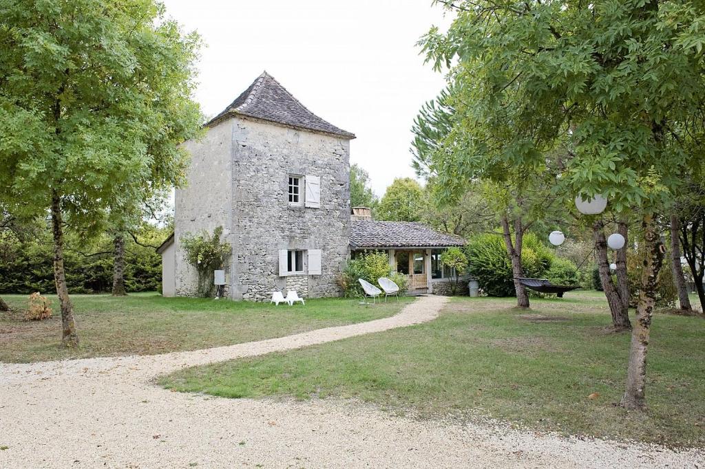 an old stone house with a dog sitting in front of it at Bassiviere Barn Chic in Saint-Étienne-de-Villeréal