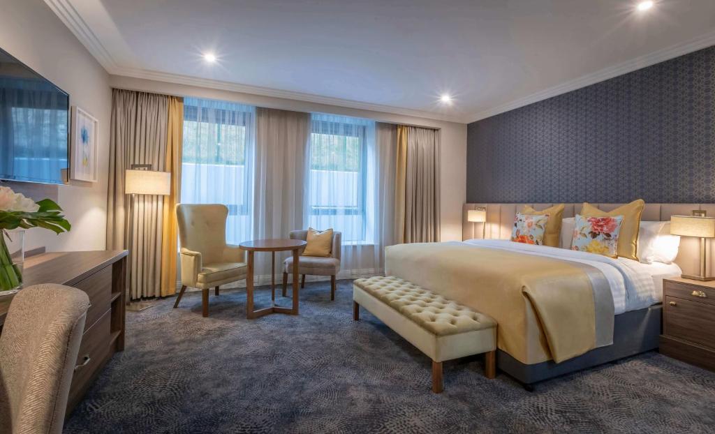 une chambre d'hôtel avec un lit, une table et des chaises dans l'établissement Castletroy Park Hotel Suites, à Limerick