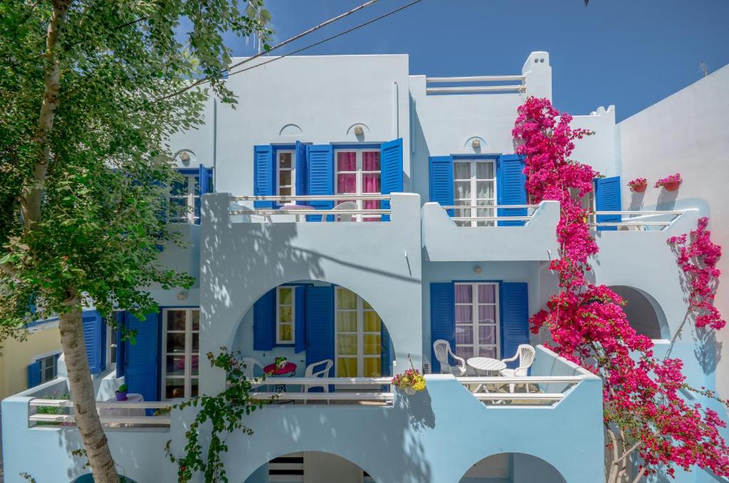 a white building with blue windows and flowers at Galazia Studios in Naxos Chora