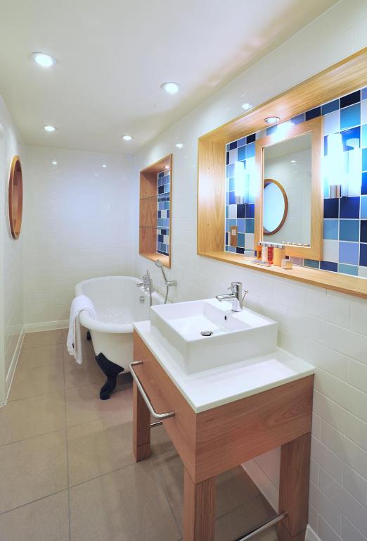 a bathroom with a tub and a sink and a mirror at The Brudenell in Aldeburgh