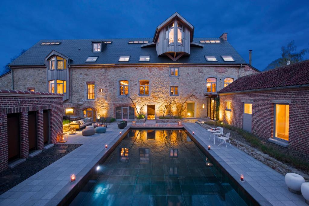 une grande maison avec une piscine en face de celle-ci dans l'établissement Ne5t Hotel & Spa, à Namur
