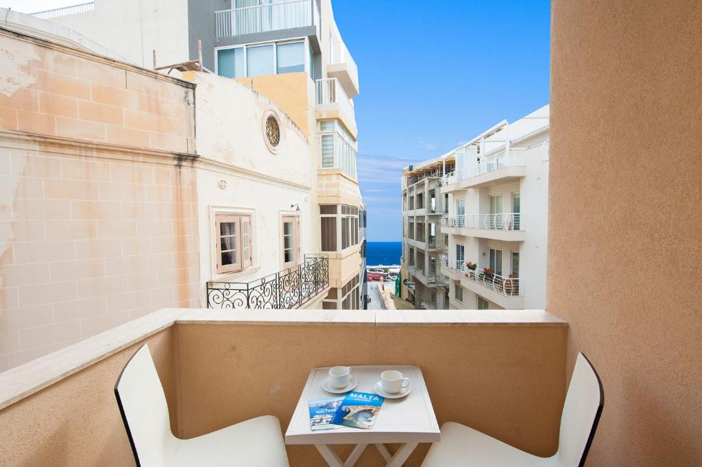 uma varanda com uma mesa e cadeiras num edifício em Alborada Apart Hotel em Sliema