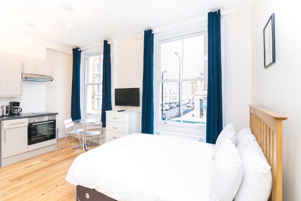 ロンドンにあるEarl's Court Studiosのベッドルーム1室(青いカーテン付きのベッド1台、キッチン付)