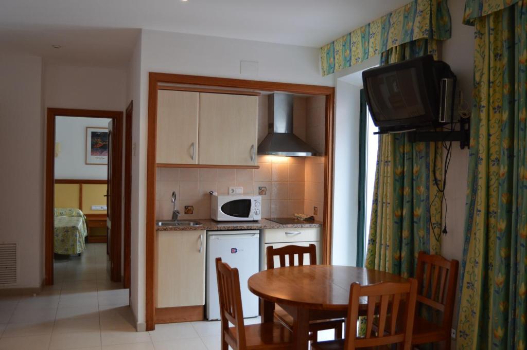 cocina y comedor con mesa y microondas en Apartamentos Royal, en Lloret de Mar