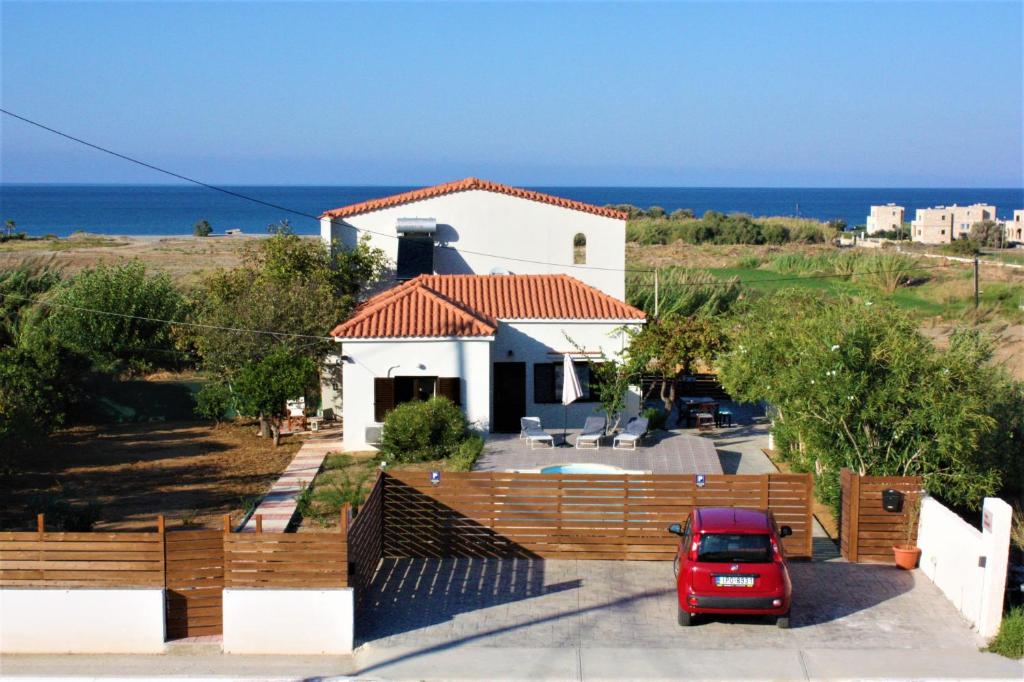 a red car parked in front of a white house at Casa Skouteli with Private pool in Kolymvari