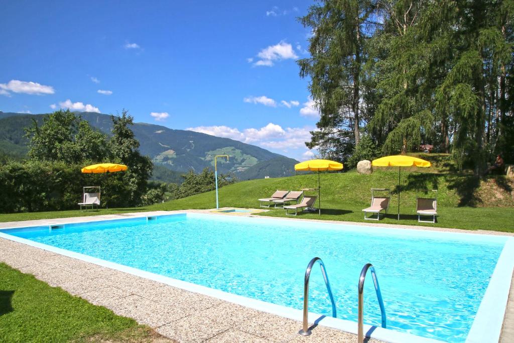 a swimming pool with chairs and umbrellas in a yard at Hotel Pichlerhof in San Lorenzo di Sebato