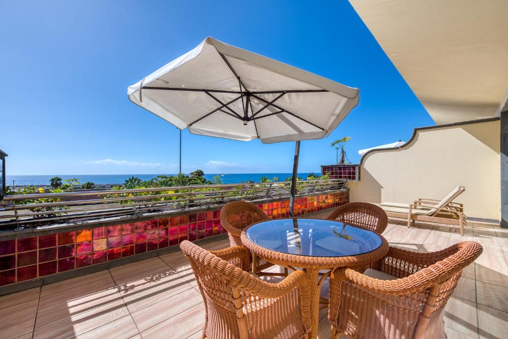 a table and chairs with an umbrella on a balcony at Holiday Club Playa Amadores in Amadores