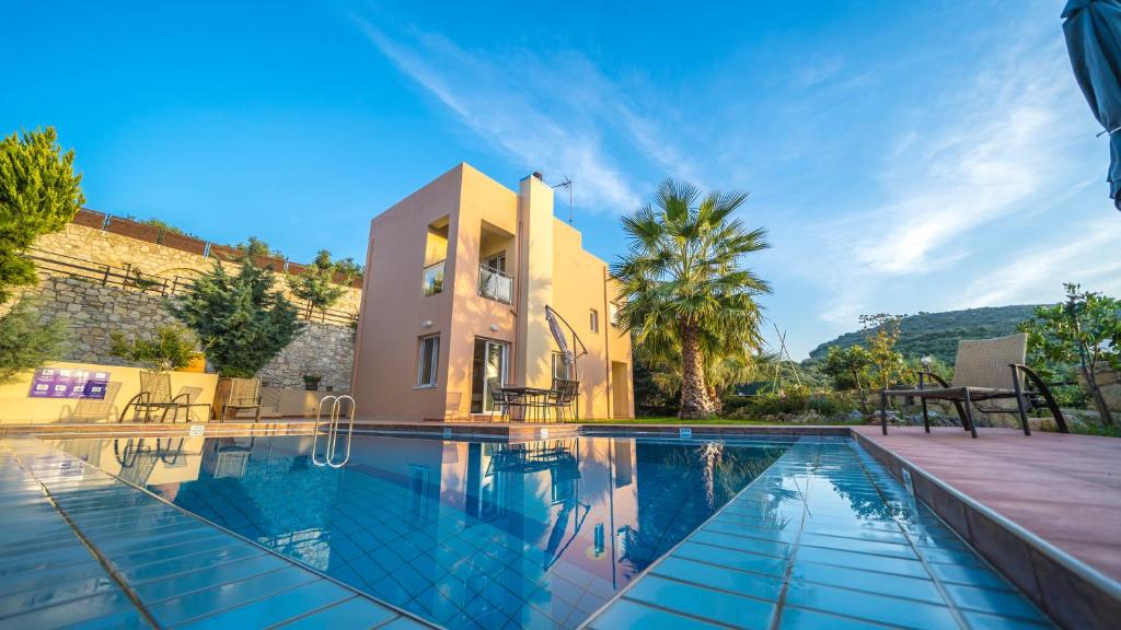 a villa with a swimming pool in front of a house at Meliades Villas in Agia Marina Nea Kydonias