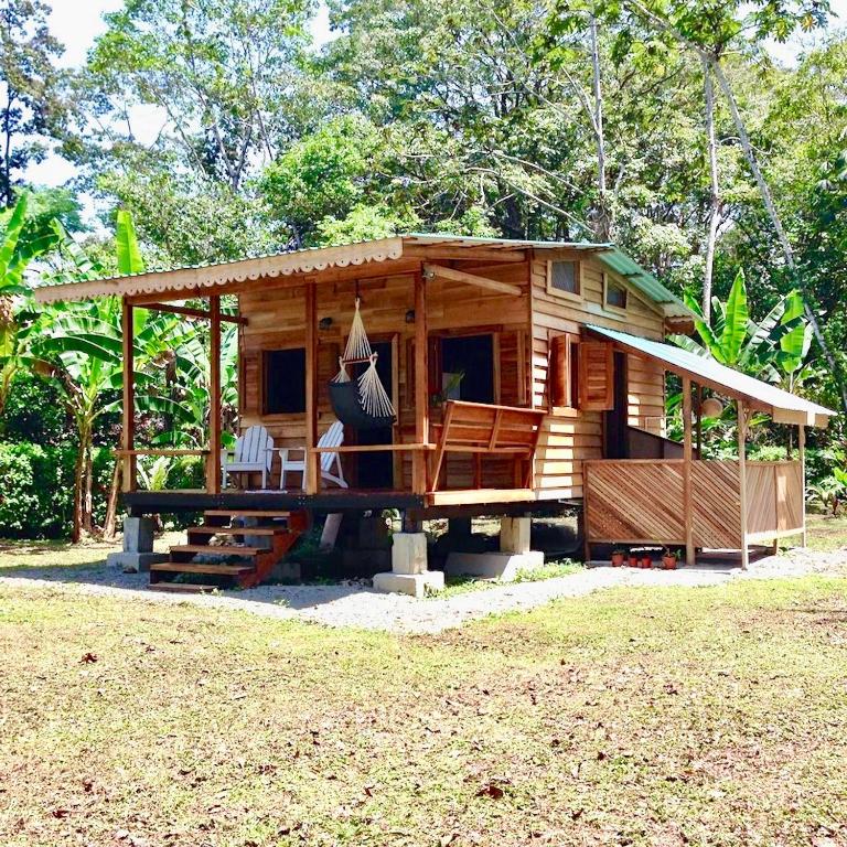 a small wooden house with a porch and a table at Casita del Mar- Caribbean Beachfront Bungalow in Chiquita Beach in Puerto Viejo