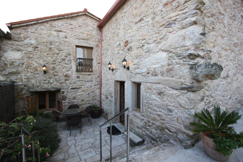 ein Steingebäude mit einem Tisch und Stühlen davor in der Unterkunft Vivienda Vacacional Vila Castriño en las Rias Baixas in Tarragona