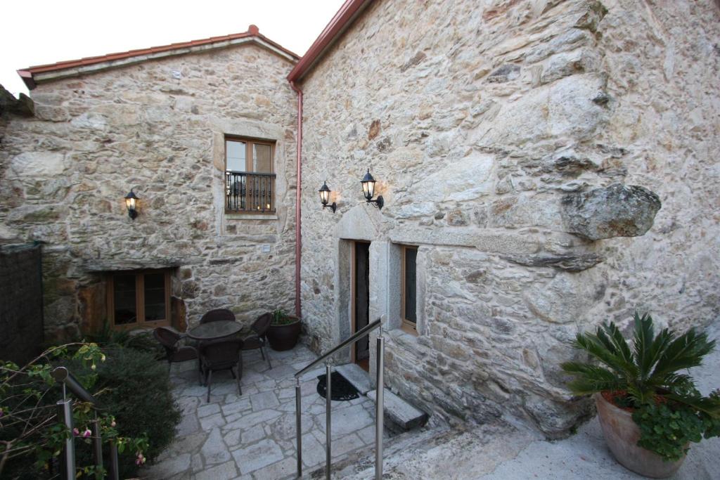 a stone building with a table and chairs in front of it at Vivienda Vacacional Vila Castriño en las Rias Baixas in Taragoña