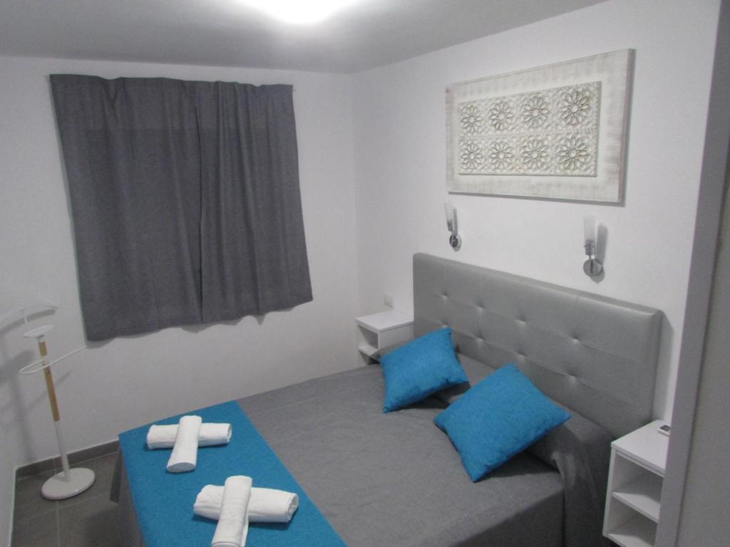 プエルトリコにあるComplejo Cumana by Placida Marの青い枕と窓付きのベッドが備わる小さな客室です。