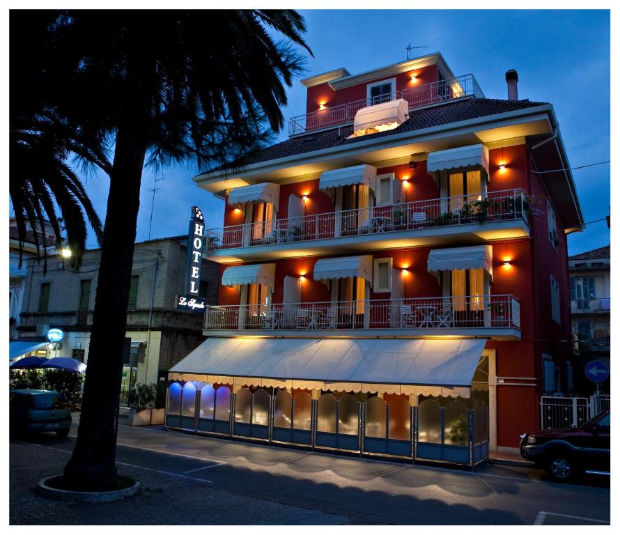 ein großes rotes Gebäude mit Balkon auf einer Straße in der Unterkunft Hotel lo Squalo in Grottammare
